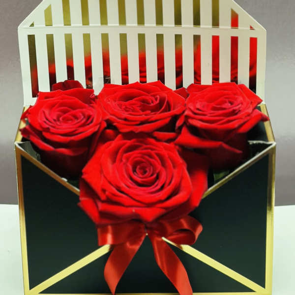 Four red roses in a black gift box with a red ribbon
