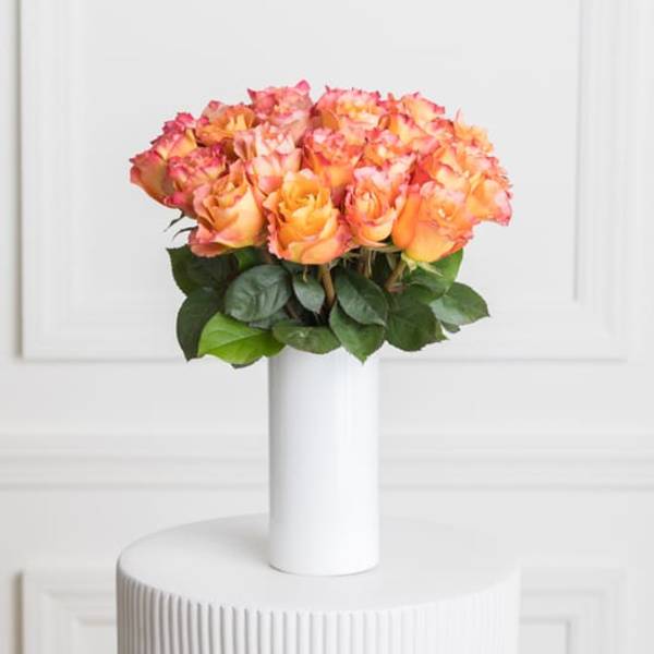 Orange and pink roses arranged in a white vase