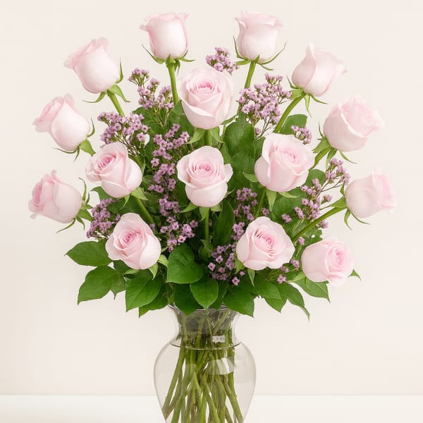 Pink roses and purple filler flowers arranged in a clear glass vase