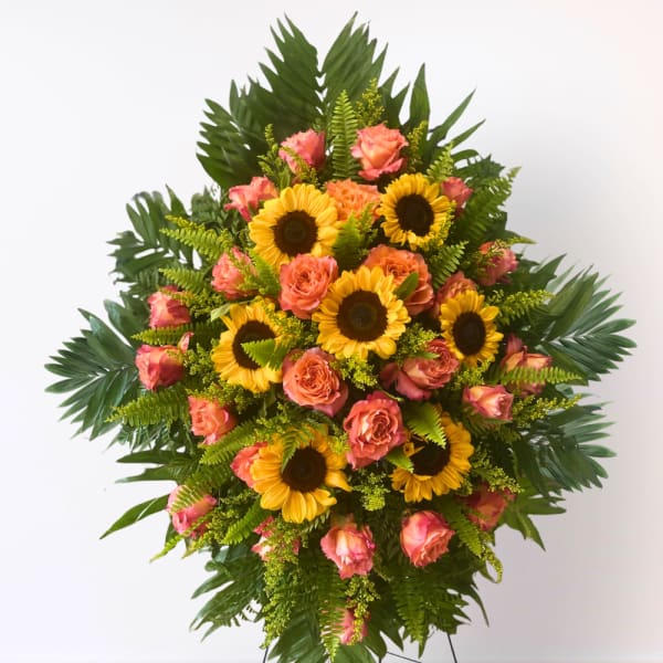 Standing floral spray with sunflowers and pink roses on a metal easel