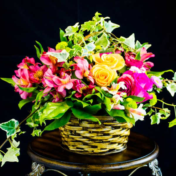 Basket arrangement of pink flowers and yellow roses with trailing ivy