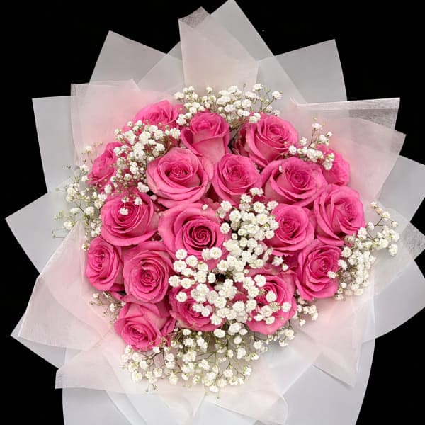 Bouquet of bright pink roses with white baby's breath in pale wrapping