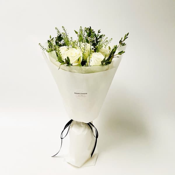 White rose bouquet wrapped in paper with a black ribbon