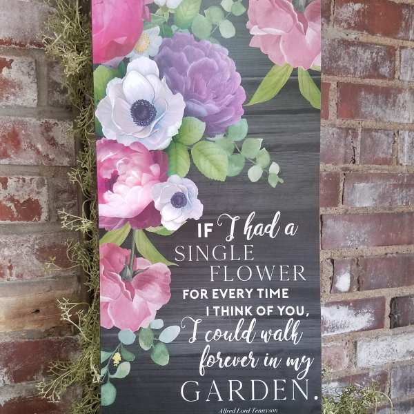 Floral wall sign with pink and purple blooms and a garden quote