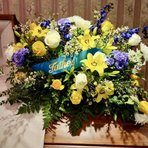 Yellow and white floral spray with a blue "Father" ribbon
