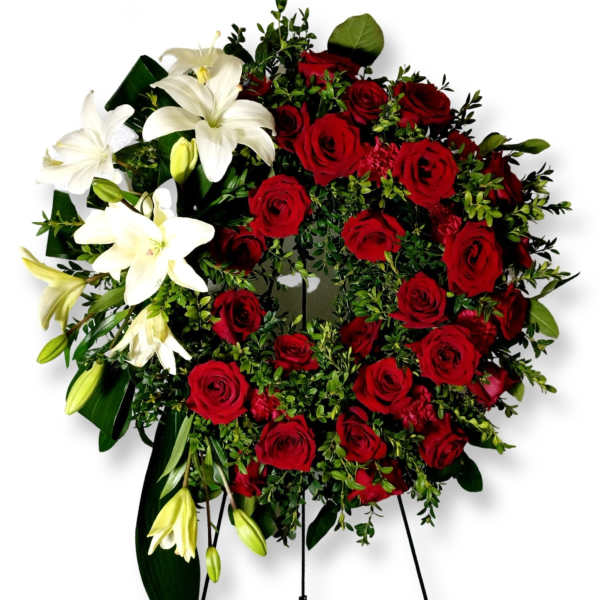 Red roses and white lilies arranged in a standing wreath on an easel