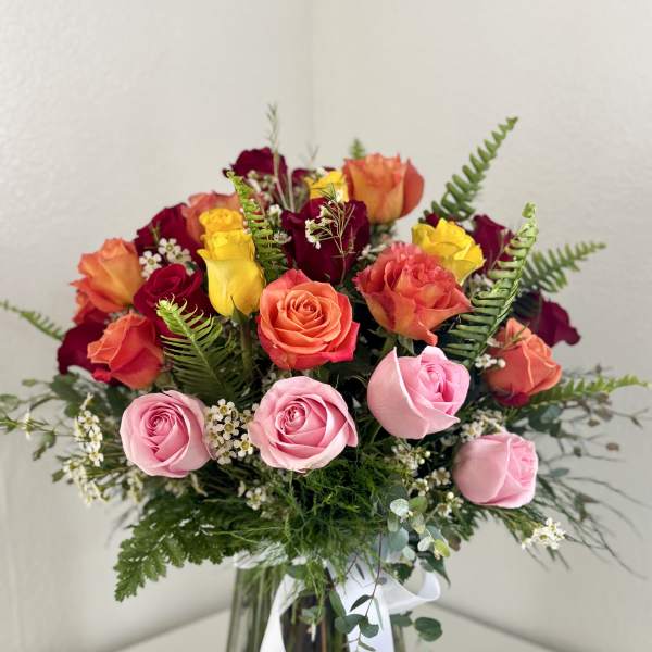 Mixed roses in pink, coral, yellow, and burgundy in a glass vase