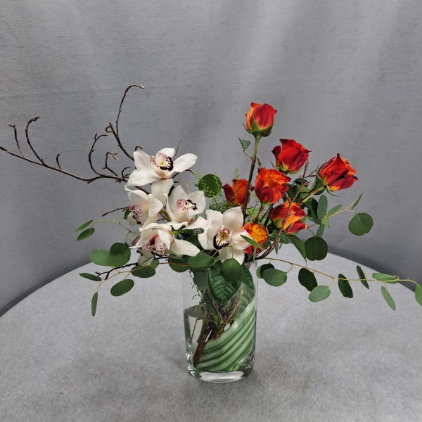 White orchids and red roses in a clear glass vase