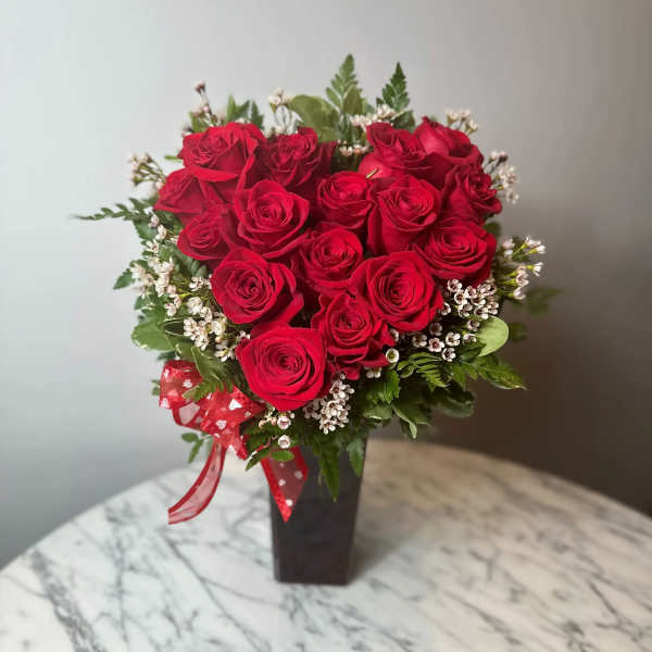 Red roses arranged in a black vase with a red ribbon