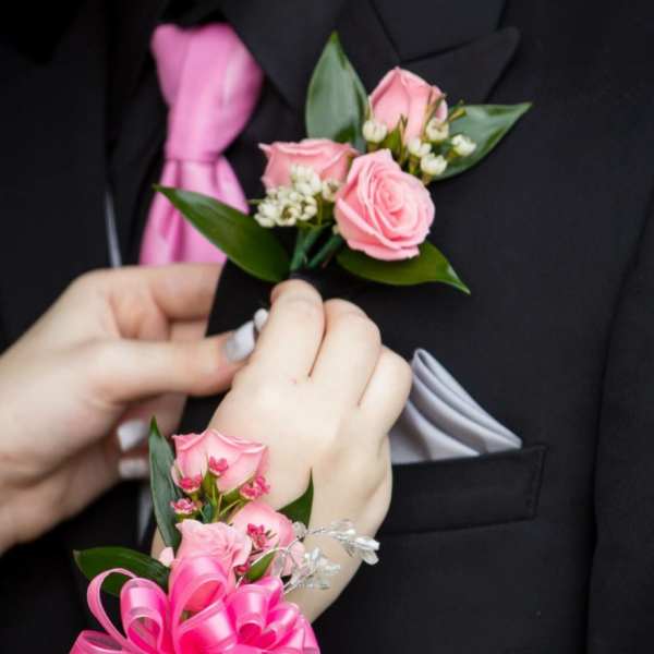 Pink rose boutonniere and corsage on a black suit and wrist