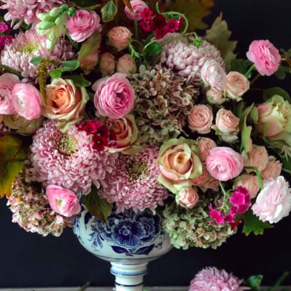 Pink and cream floral arrangement in a blue-and-white pedestal vase