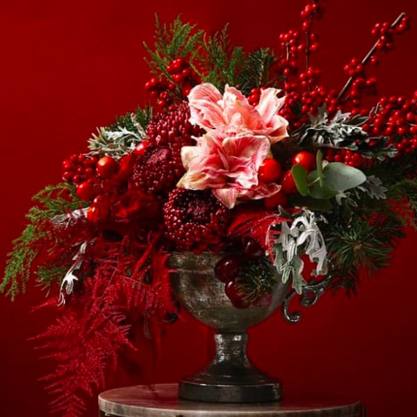 Red and pink floral arrangement in a dark urn vase