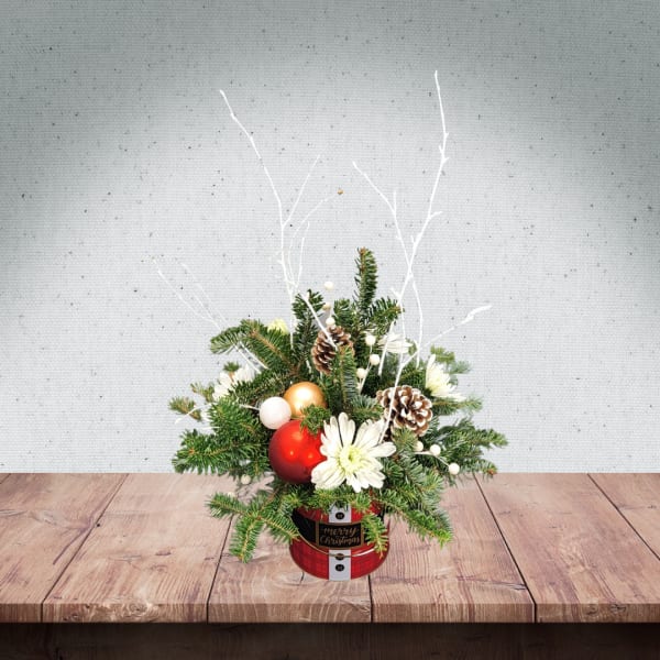 Christmas arrangement with pine, white flowers, and ornaments in a red tin container