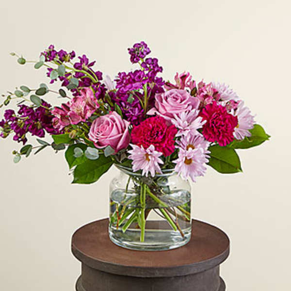 Pink and purple flowers arranged in a clear glass vase