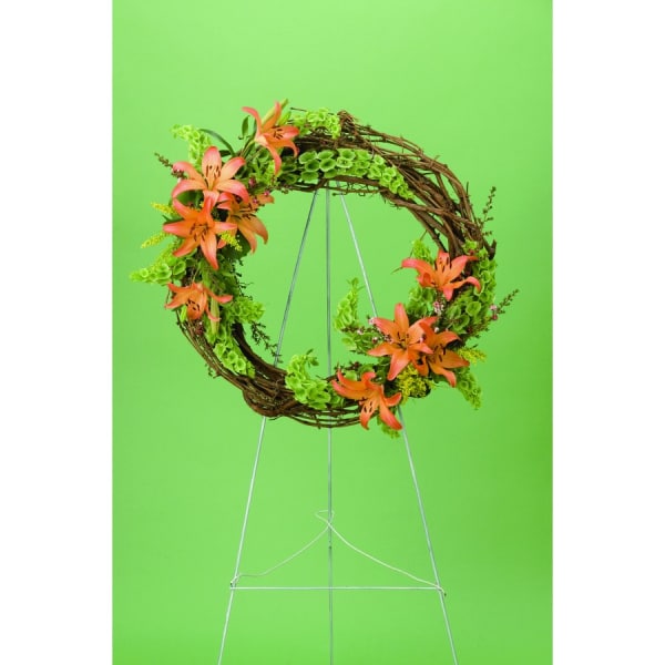 Circular floral wreath with orange lilies on a wire stand