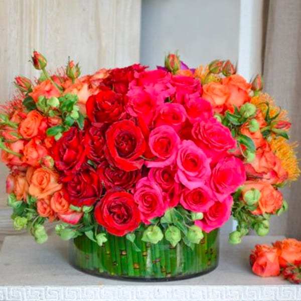 Large bouquet of red, pink, and orange roses in a glass vase