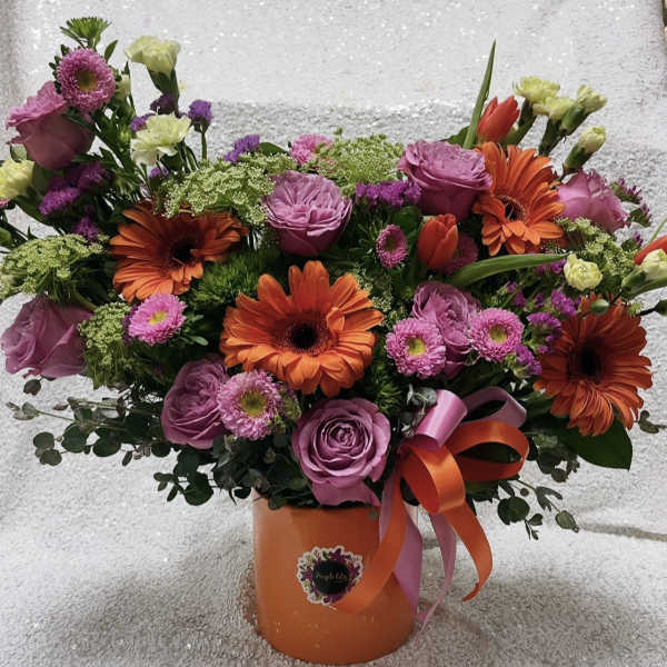 Bouquet of pink roses and orange gerbera daisies in an orange vase