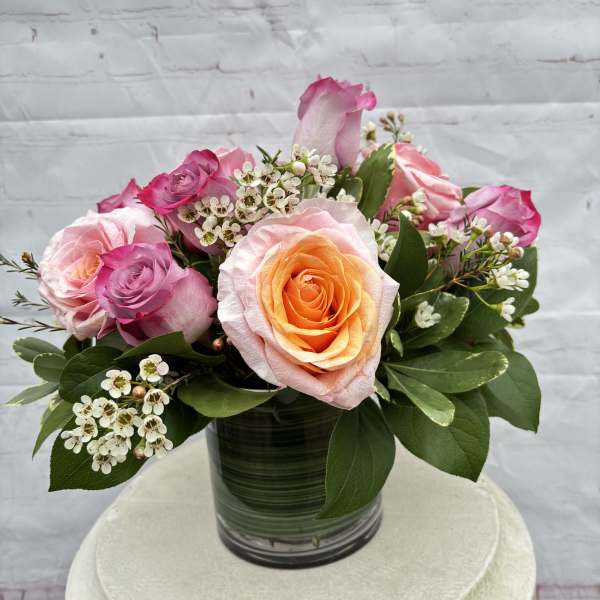 Pink and peach roses arranged in a glass vase