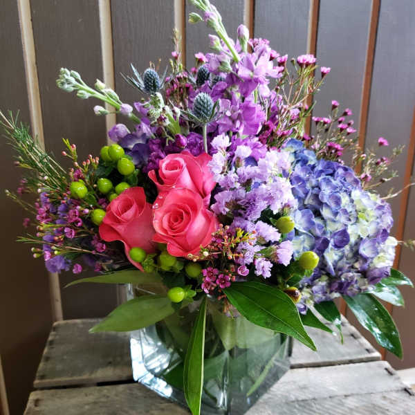 Mixed bouquet with pink roses and purple hydrangea in a glass vase