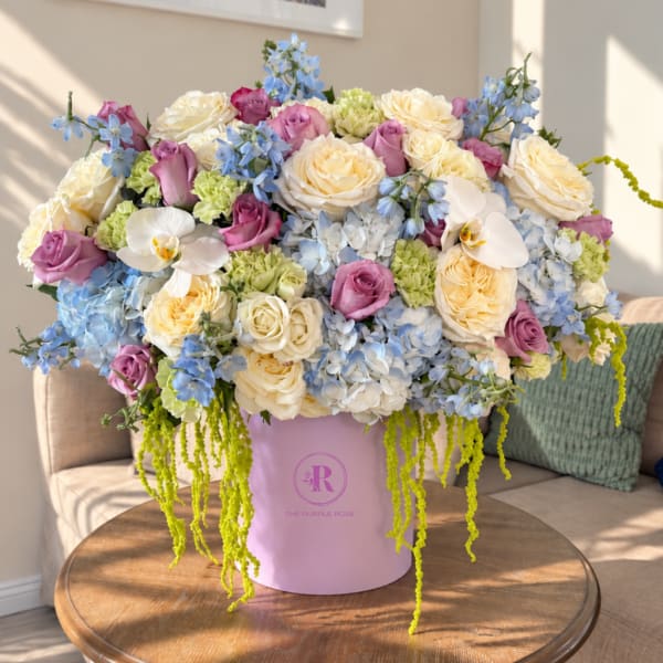 Large pastel flower arrangement in a pink hat box on a table