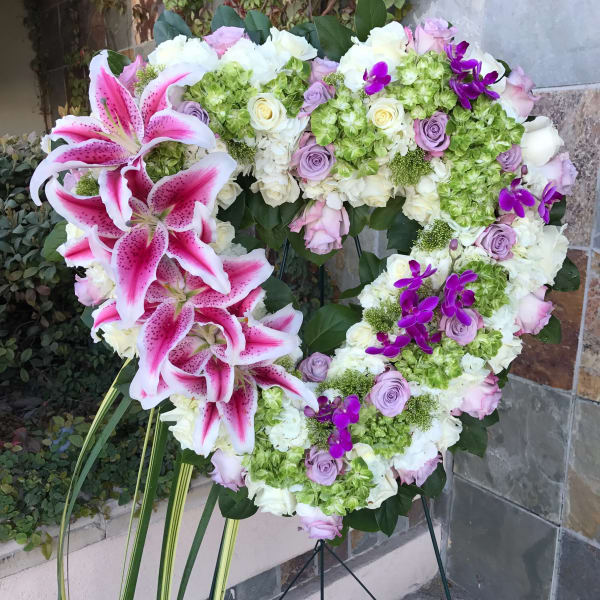 Heart-shaped floral wreath with pink lilies, roses, hydrangeas, and purple orchids
