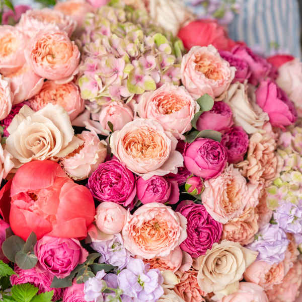 Large bouquet of pink and peach roses with a coral peony