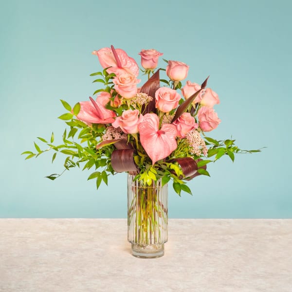 Pink roses and anthuriums arranged in a clear glass vase