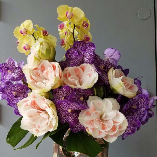Bouquet of yellow and purple orchids in a silver vase