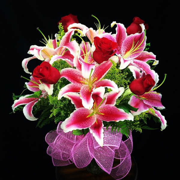Bouquet of pink lilies and red roses with a purple ribbon wrap