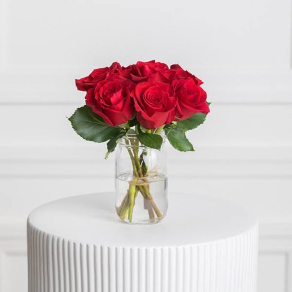Red roses arranged in a clear glass vase