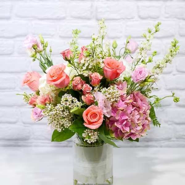 Pink and peach roses with hydrangea in a clear glass vase