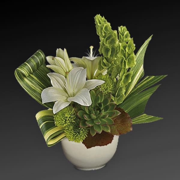 White lilies and green succulents in a white vase