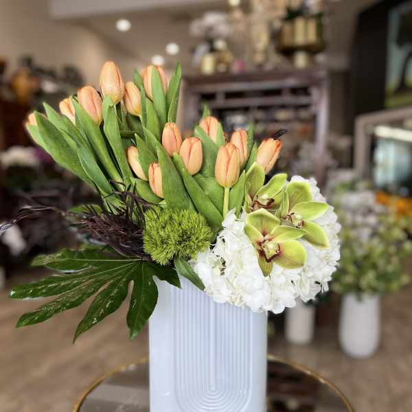 Peach tulips and white hydrangeas in a white vase
