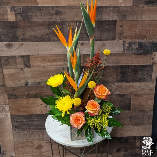Tropical bouquet with orange bird of paradise, yellow mums, and peach roses