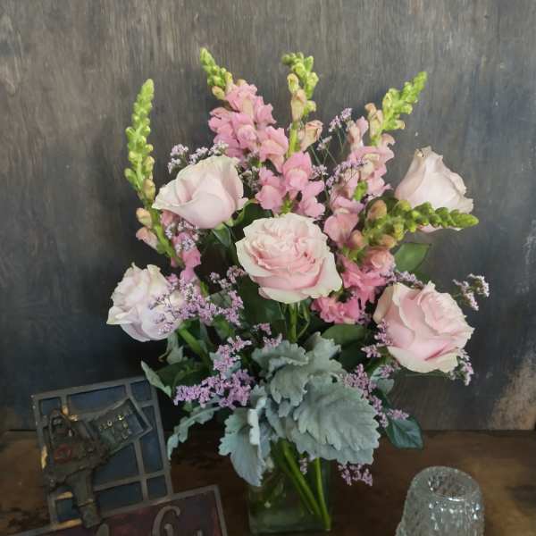 Pink roses and snapdragons arranged in a glass vase