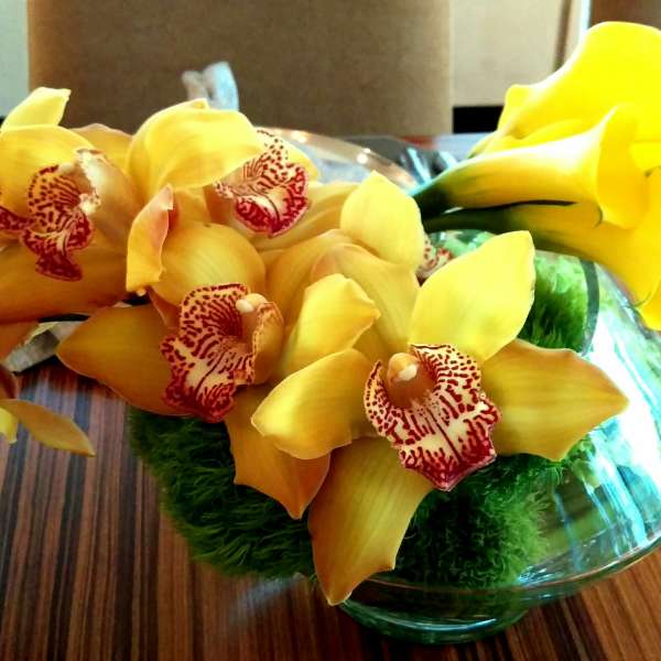 Yellow orchids arranged in a low glass bowl centerpiece