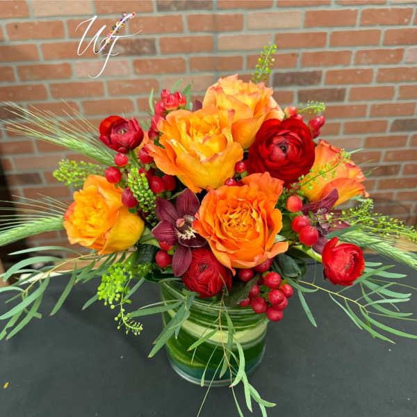 Orange and red floral arrangement in a glass vase