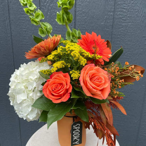 Orange and white floral arrangement in a vase with tall green spikes