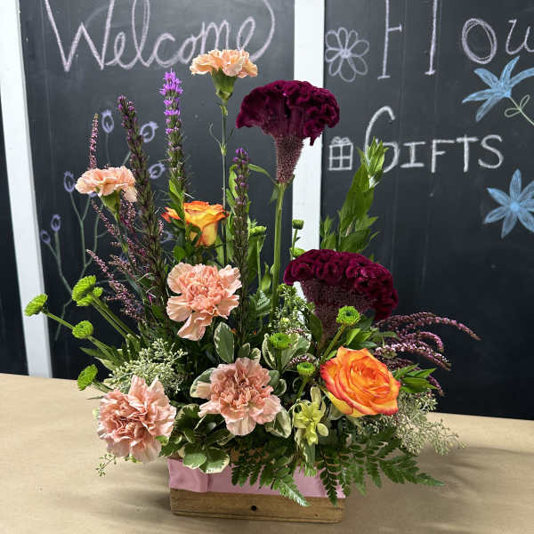 Mixed floral arrangement in a wooden box with peach, orange, and burgundy blooms