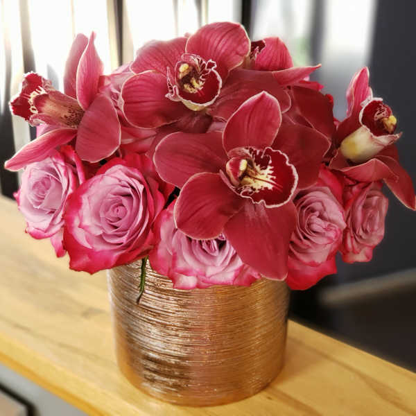 Pink roses and red orchids arranged in a gold vase