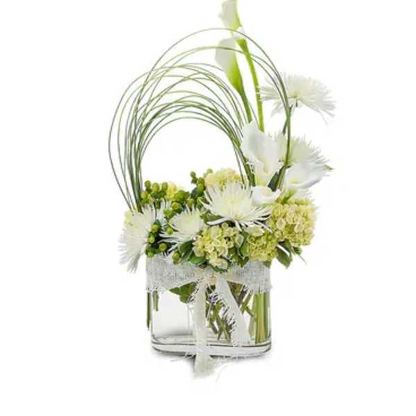 White flowers arranged in a clear glass vase with arched grass stems
