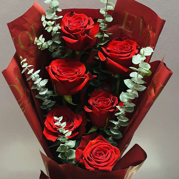 Bouquet of red roses wrapped in burgundy paper with eucalyptus accents