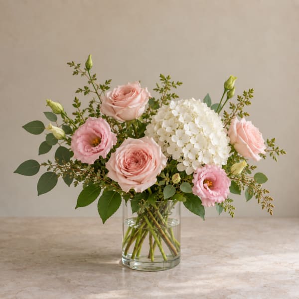 Pink roses and lisianthus with white hydrangea in a clear glass vase