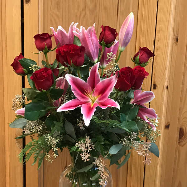 Bouquet of red roses and pink lilies in a clear glass vase