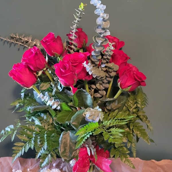 Pink roses in a glass vase with eucalyptus and fern accents
