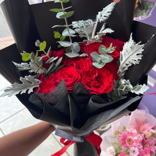 Red rose bouquet wrapped in black paper with silver foliage