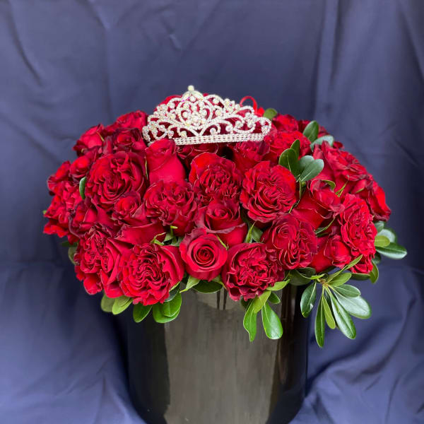 Red rose arrangement in a black vase with a jeweled tiara topper