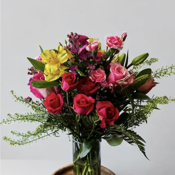 Mixed bouquet of pink and yellow flowers in a clear glass vase