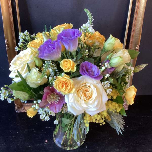 Bouquet of roses and purple lisianthus in a clear glass vase