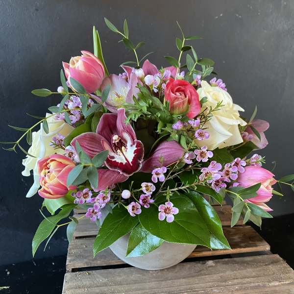 Pink and white tulips with roses and orchids in a round vase